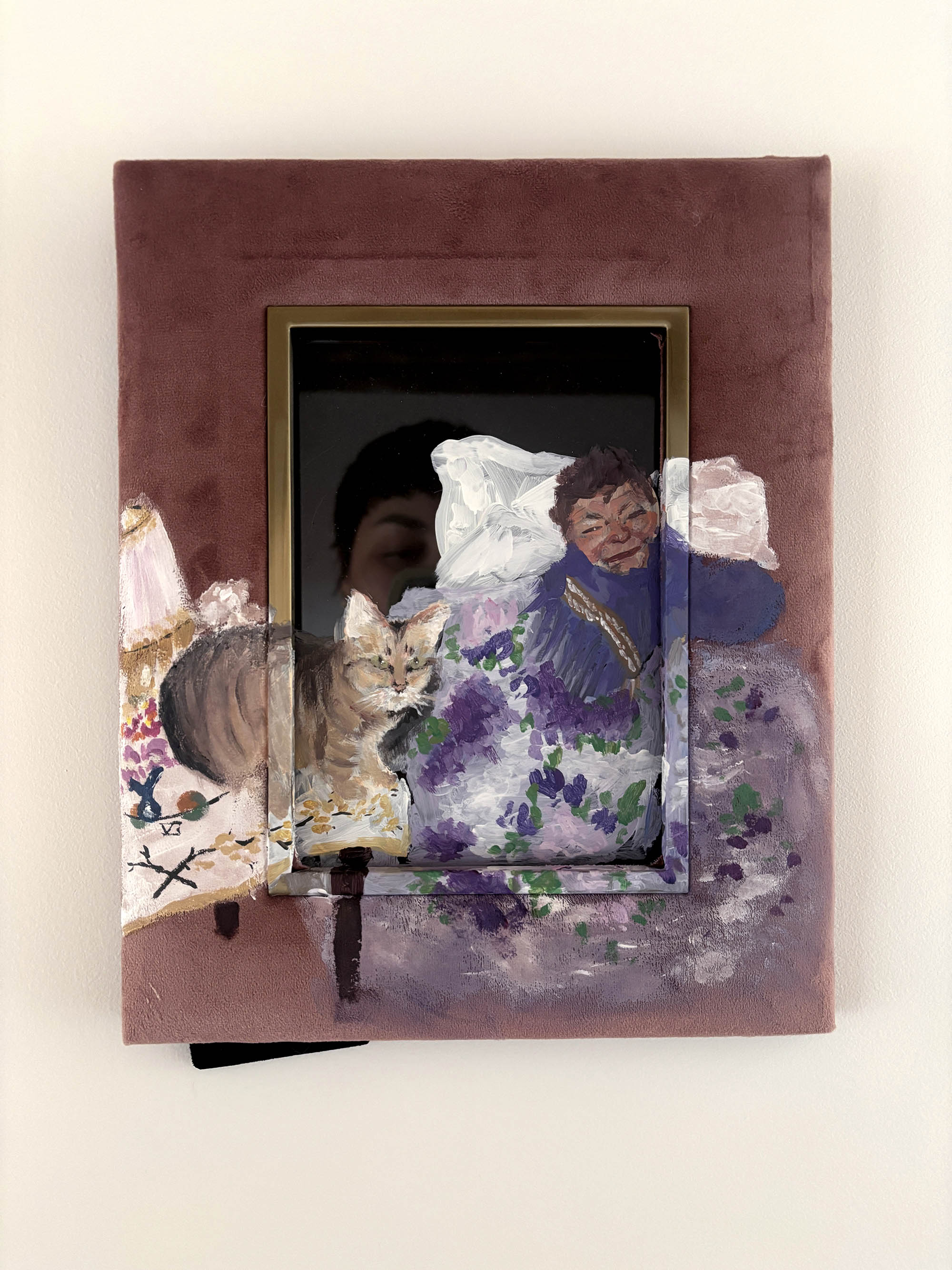 sur un cadre en velours rose, une peinture d'un chat assis sur une table et d'une vieille femme allougé sur son lit, emmitouflée dans ses draps et son écharpe violette. La peitnure ne prends pas tout le cadre, le visage d'une femme se reflète dans la vitre, au dessus du chat.